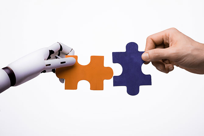 Legal Eagle Spotlight: AI-Powered M&A; A robotic hand and a human hand each hold interlocking puzzle pieces, orange and blue, symbolizing collaboration between technology and humans.