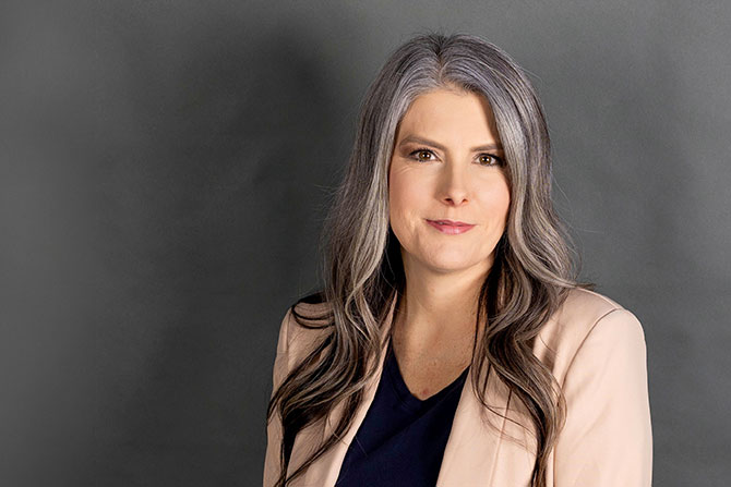 Meet Your Missouri Banker: Cynthia Ramsey; Woman with long gray hair wearing a beige blazer and dark top, smiles softly against a gray background. The tone is professional and approachable.