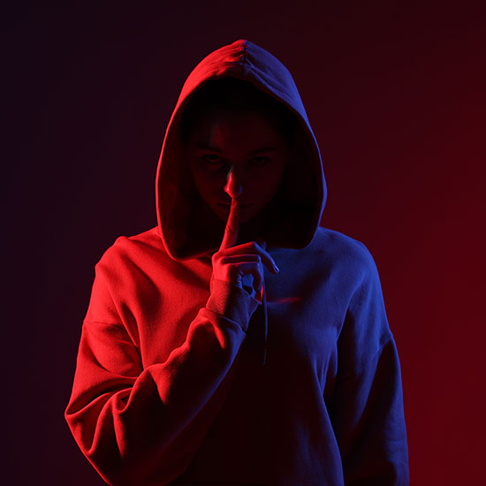Hacker in a hoody lit from left by red light and the right by blue light