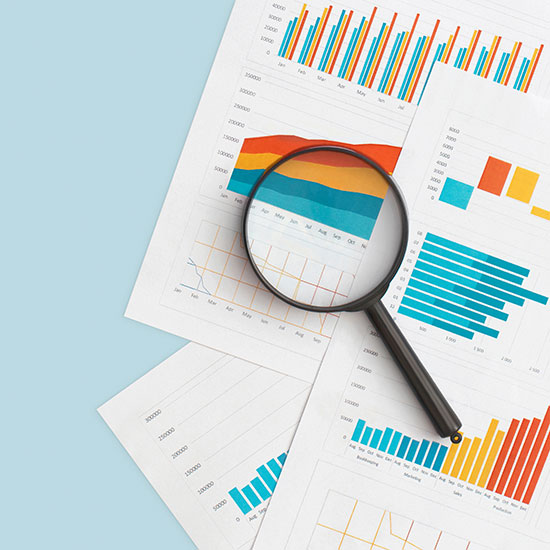 Charts and graphs under a handheld magnifying glass